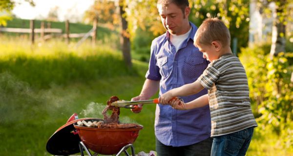 Vater und Sohn grillen Fleisch.