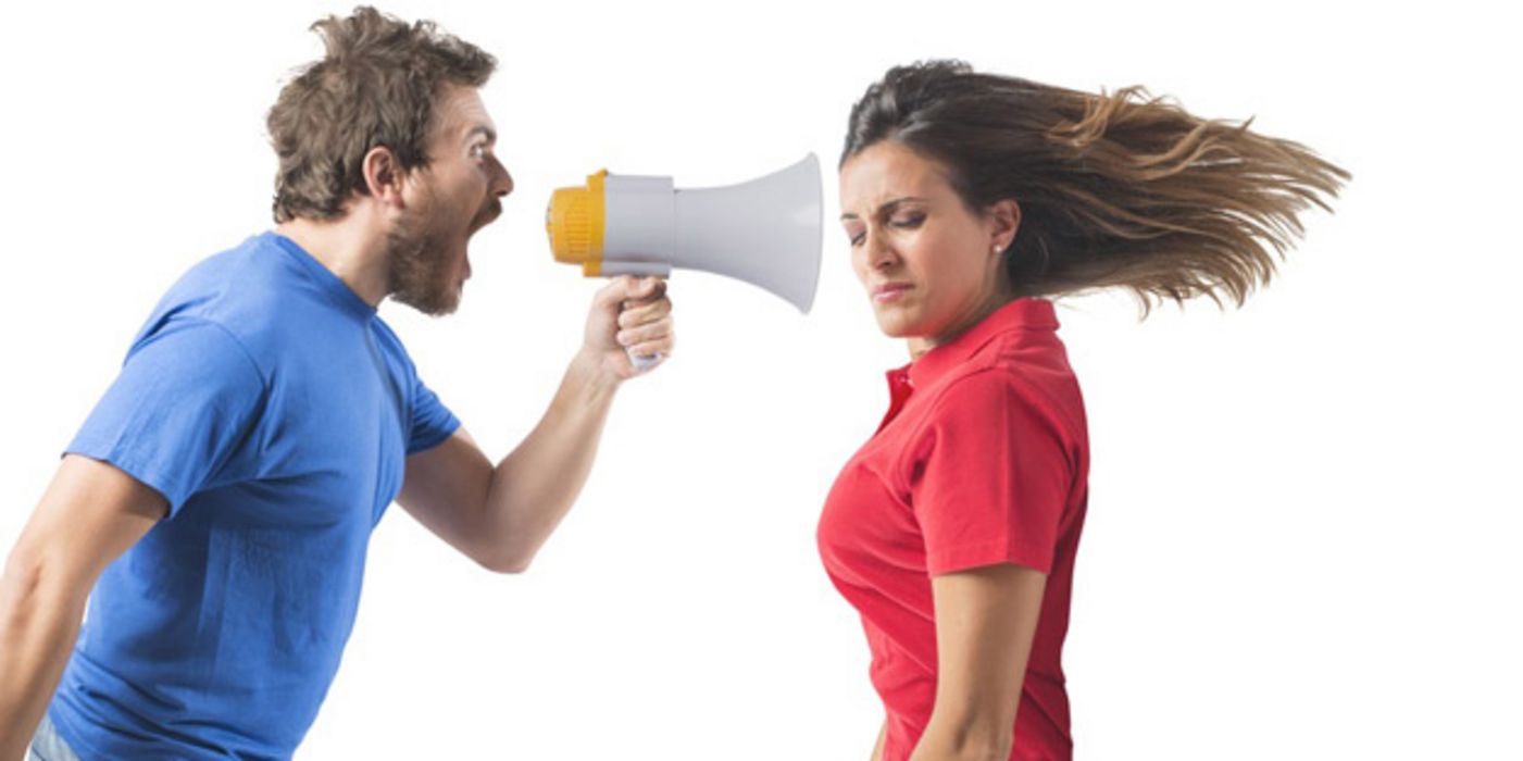 Profilfoto Mann im blauen Shirt schreit Frau (rotes Poloshirt) durch ein Megaphon an; ihre langen braunen Haare fliegen waagrecht nach hinten, Augen geschlossen, Gesicht zur Kamera gedreht