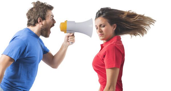 Profilfoto Mann im blauen Shirt schreit Frau (rotes Poloshirt) durch ein Megaphon an; ihre langen braunen Haare fliegen waagrecht nach hinten, Augen geschlossen, Gesicht zur Kamera gedreht