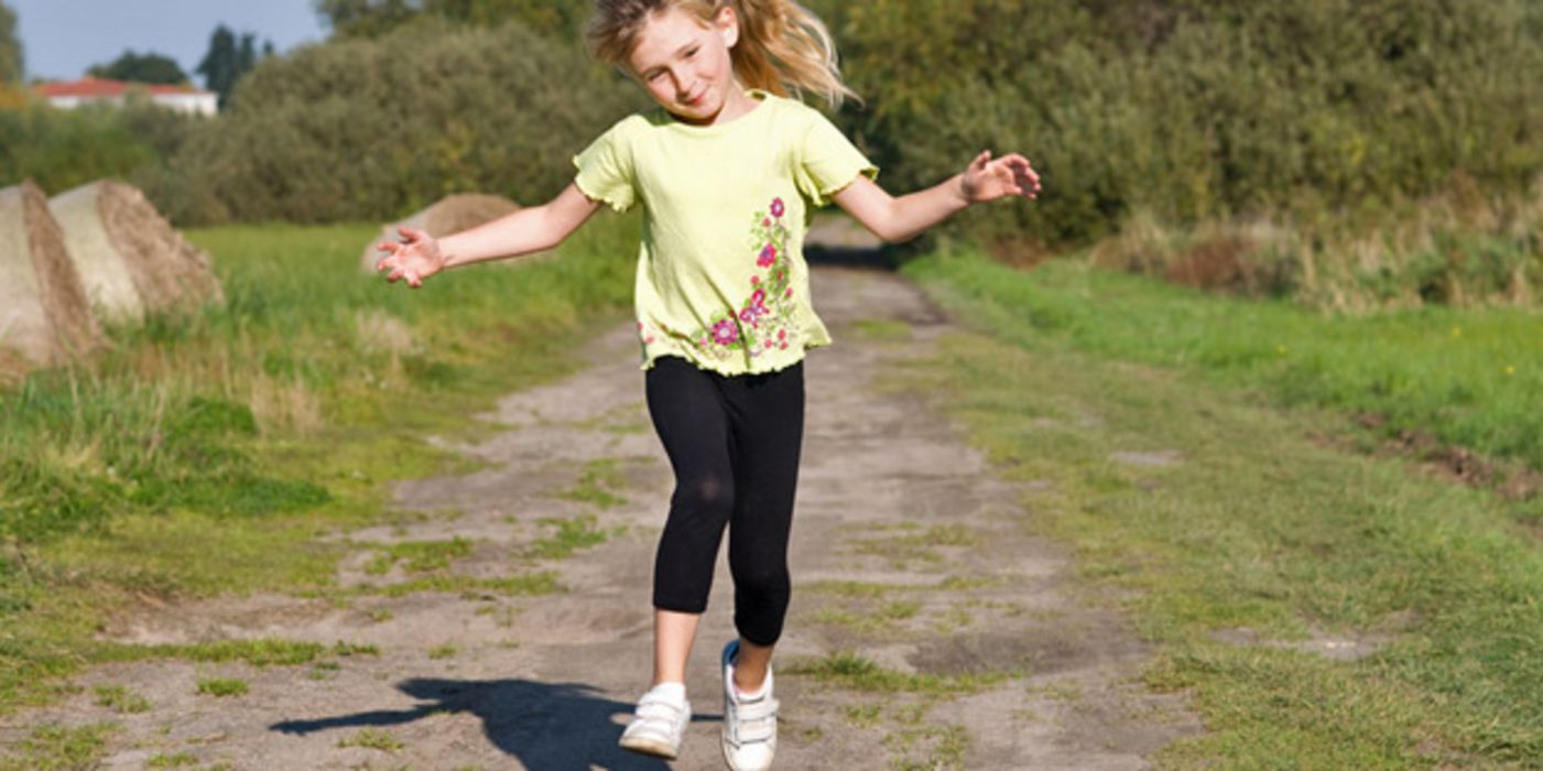 Kleines Mädchen hüpft einen Feldweg entlang