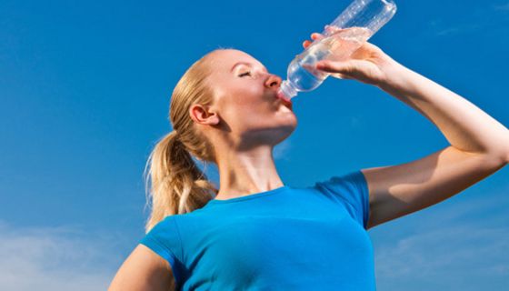 Sportliche Frau trinkt aus Wasserflasche.