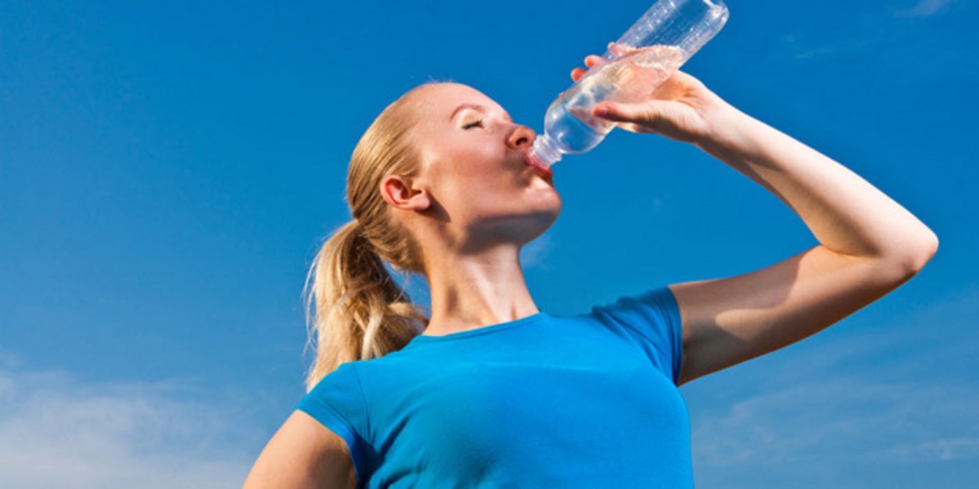 Sportliche Frau trinkt aus Wasserflasche.