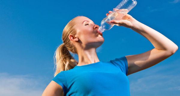 Sportliche Frau trinkt aus Wasserflasche.