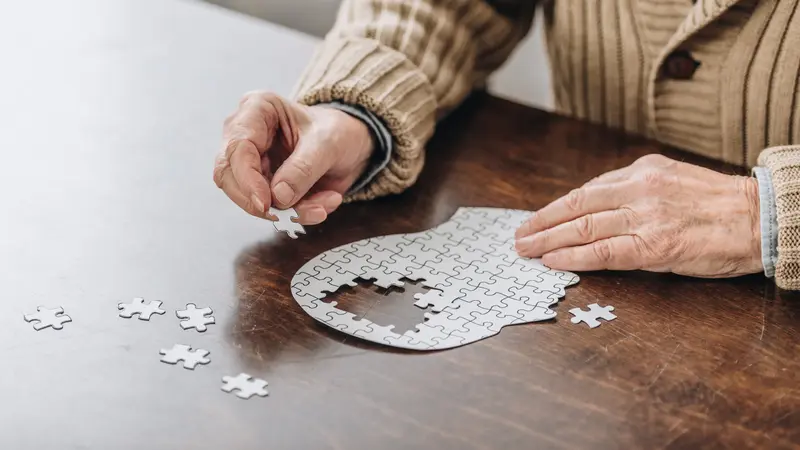 Mensch legt ein kopfförmiges Puzzle.