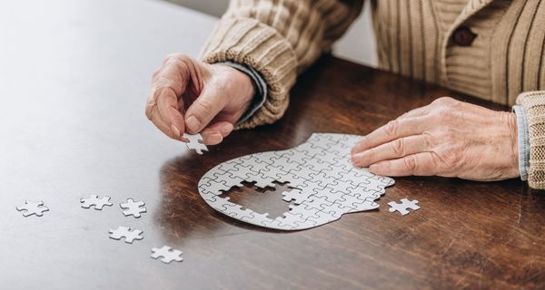 Mensch legt ein kopfförmiges Puzzle.