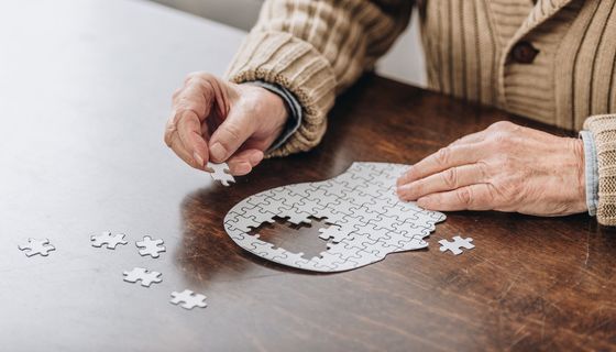 Mensch legt ein kopfförmiges Puzzle.