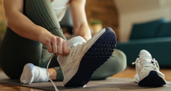 Frau zieht sich Sportschuhe an.