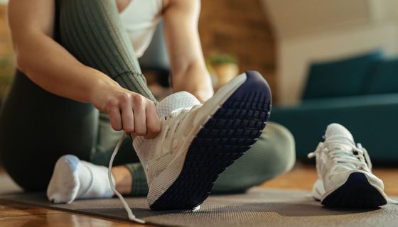 Frau zieht sich Sportschuhe an.