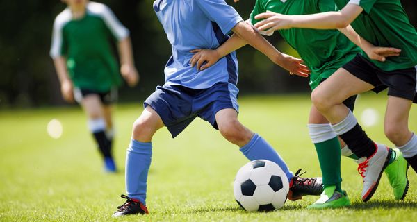 Jugendliche kämpfen beim Fußballspielen um den Ball.