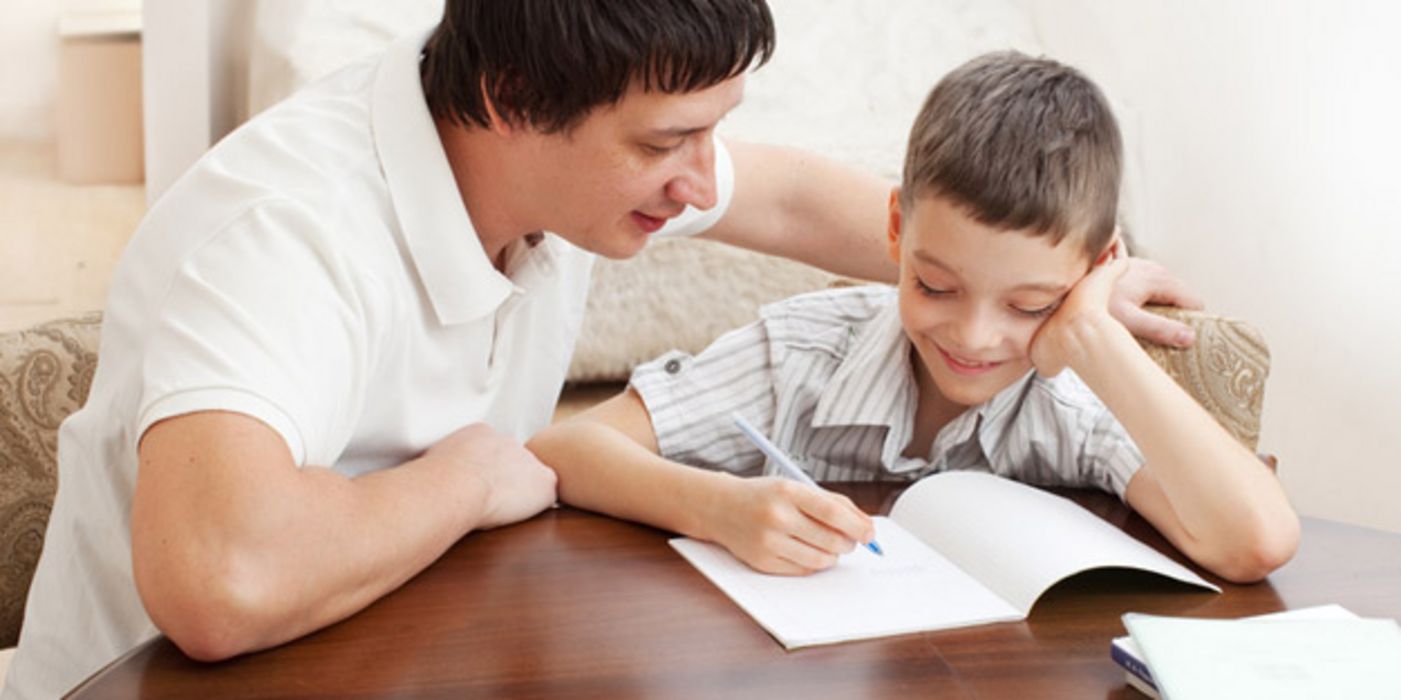 Vater hilft seinem ca. 9-jährigen Sohn bei den Hausaufgaben