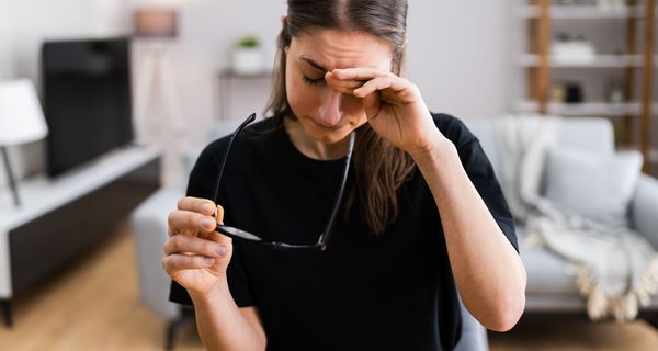 Junge Frau, reibt sich die Augen, ist erschöpft.