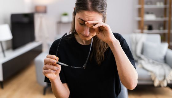 Junge Frau, reibt sich die Augen, ist erschöpft.