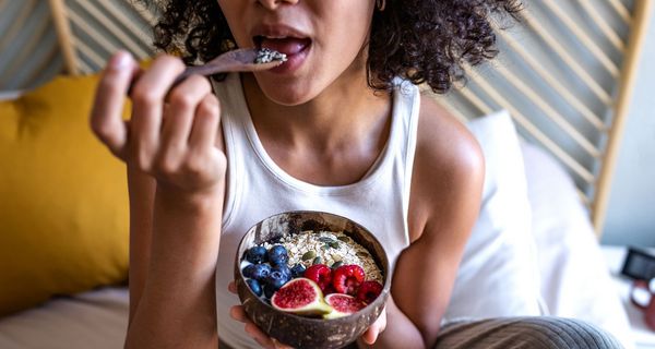 Frau, isst ein gesundes Müsli mit Obst.