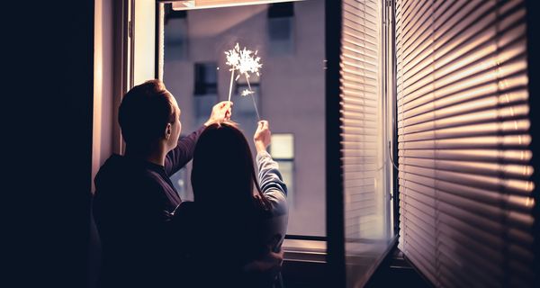 Pärchen, hält Wunderkerzen aus dem Fenster.