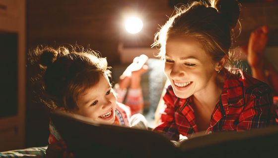 Mutter und Tochter, zusammen mit einem Buch im Bett.