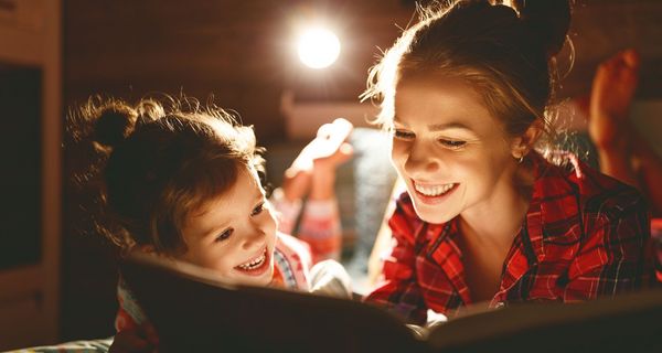 Mutter und Tochter, zusammen mit einem Buch im Bett.