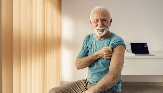 Senior, zeigt seinen Arm mit einem Pflaster.