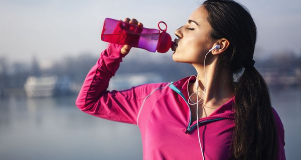 Sportliche Frau, trinkt aus einer Trinkflasche.