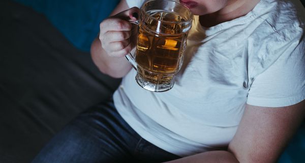 Übergewichtige Frau mit einem großen Glas Bier.