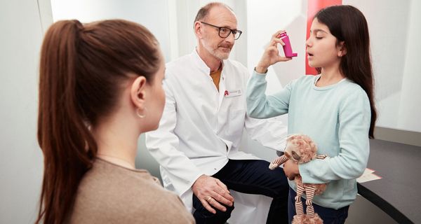 Kind, übt in der Apotheke, einen Inhalator zu benutzen.