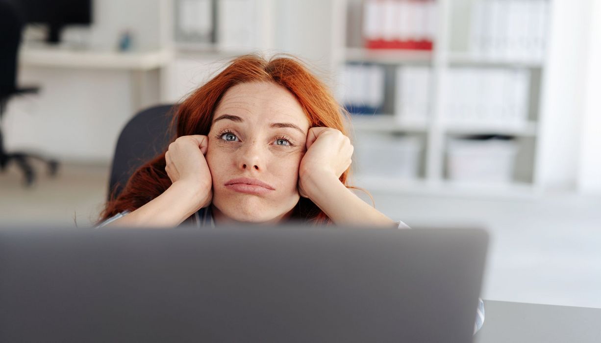 Junge Frau vor dem Laptop, erschöpft.