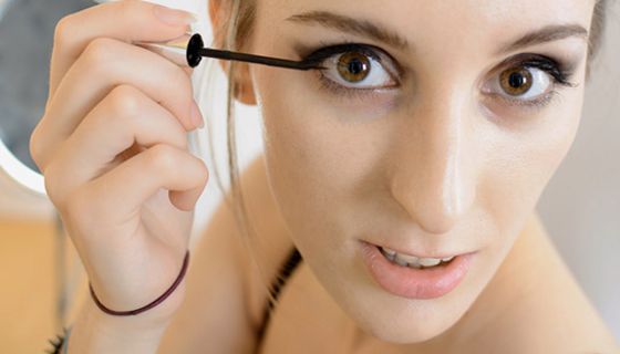 Nahaufnahme Gesicht junge Frau beim Auftragen von Eyeliner