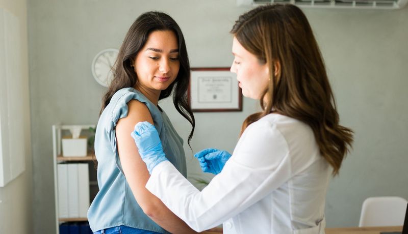 Ärztin bereitet Frau auf Grippeimpfung vor.