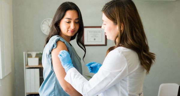 Ärztin bereitet Frau auf Grippeimpfung vor.