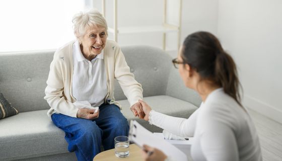 Altere Frau im Gespräch mit einer Therapeutin auf dem Sofa