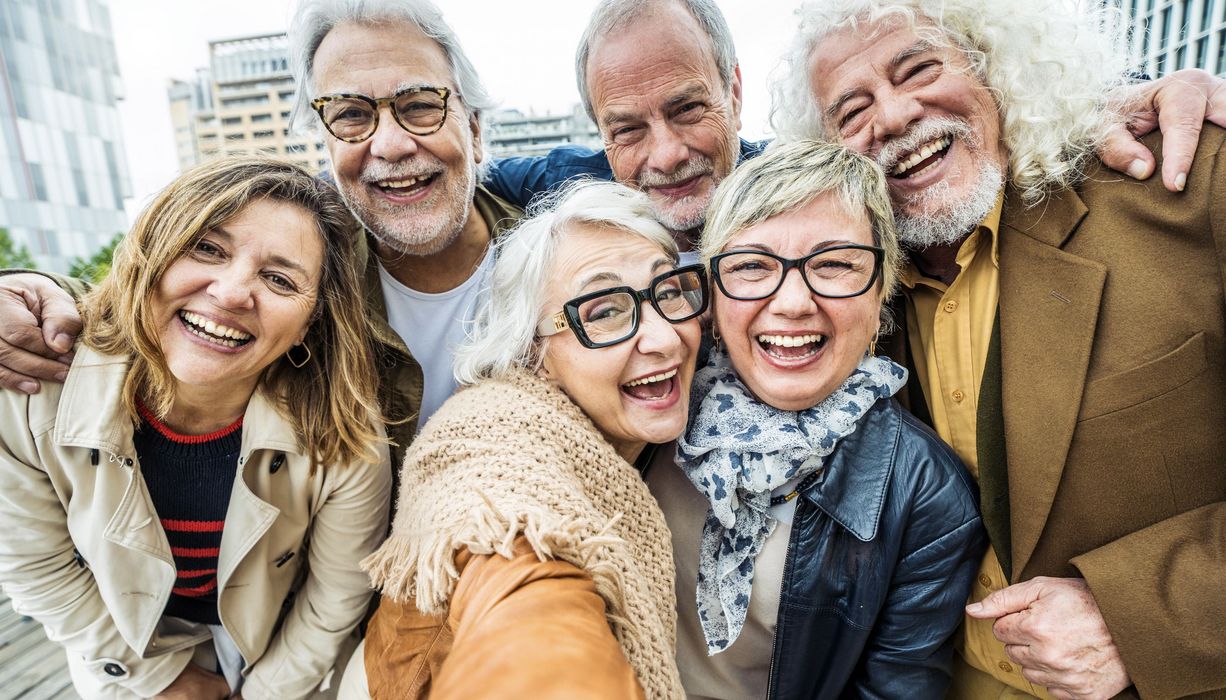 Eine Gruppe älterer Menschen macht ein Selfie und lacht.