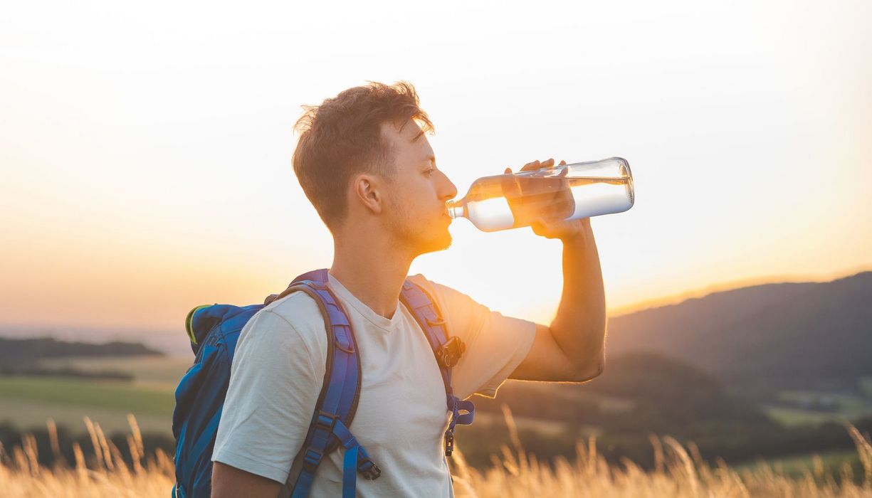 Junger Mann trinkt Wasser aus der Flasche.