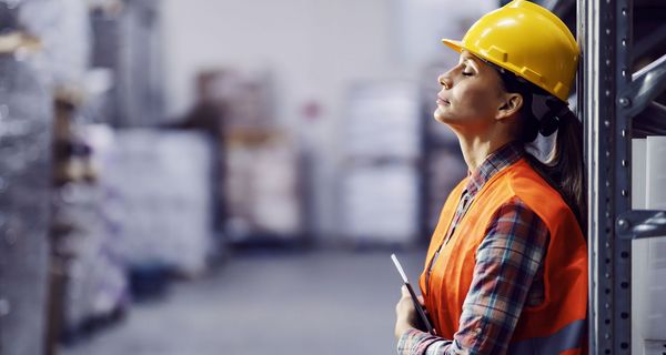 Frau auf der Baustelle, lehnt sich erschöpft gegen eine Wand.