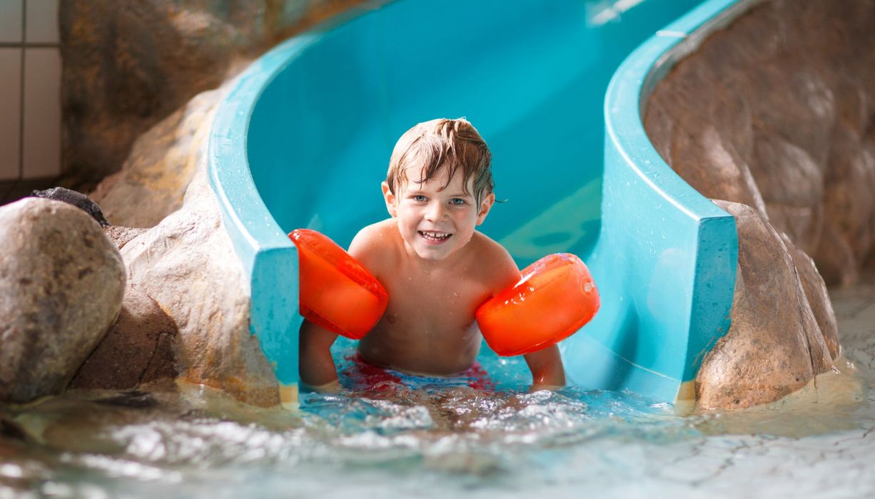 Junge, rutscht eine Wasserrutsche herunter.