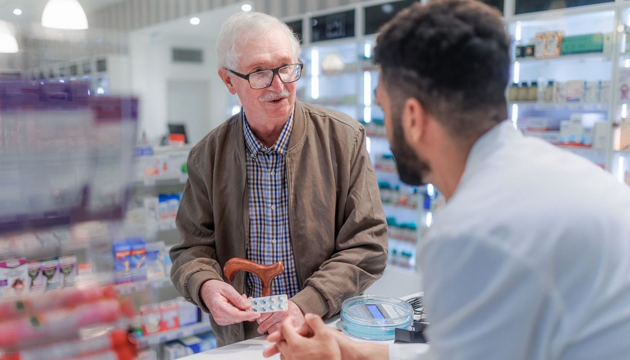 Apotheker brät älteren Mann.