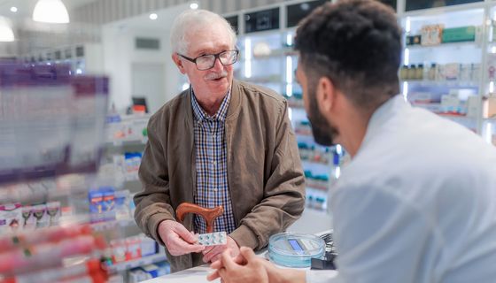 Apotheker brät älteren Mann.
