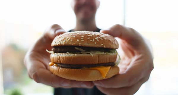 Mann, hält Hamburger in die Kamera.