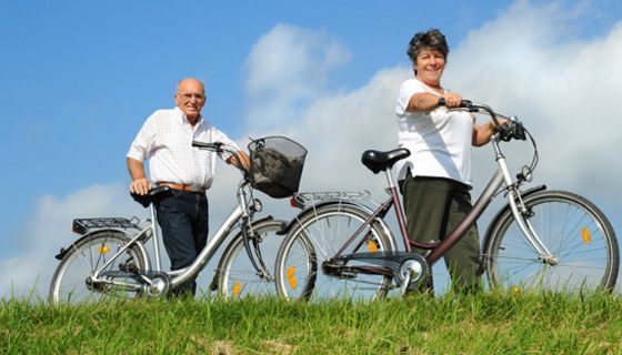 Seniorenpaar mit Fahrrädern unterwegs.