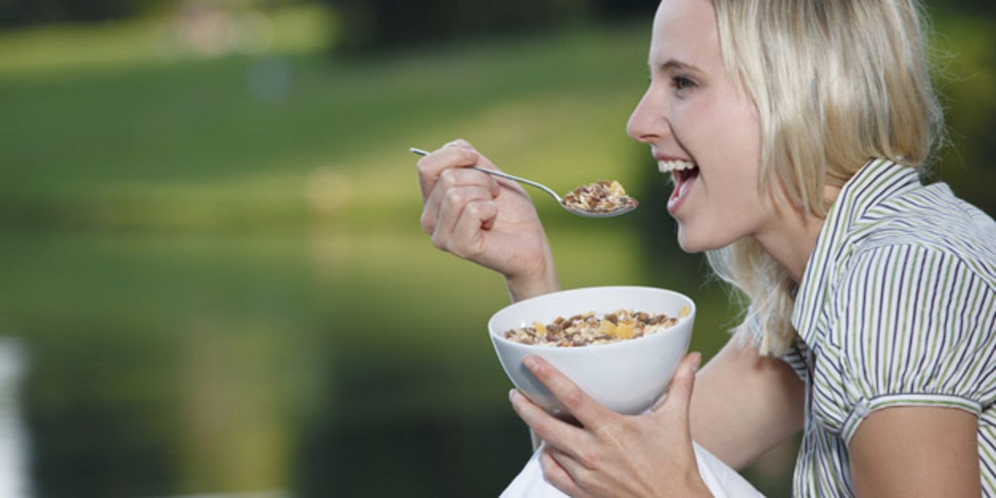 Junge Frau löffelt Müsli aus einer Schale