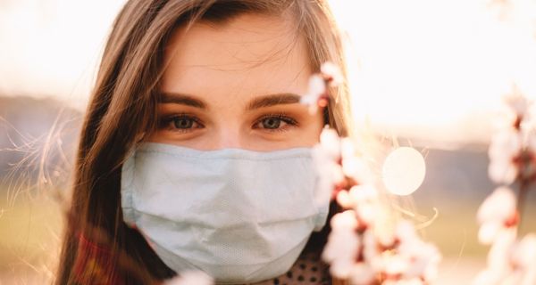 Junge Frau mit Maske, draußen im Frühling.