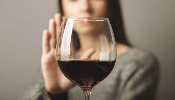 Frau, lehnt ein Glas Rotwein ab.