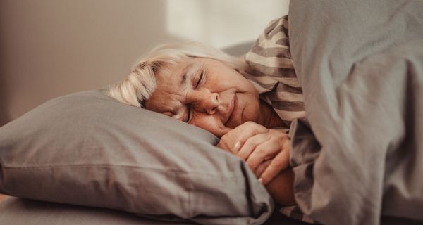 Frau, liegt im Bett und schläft.