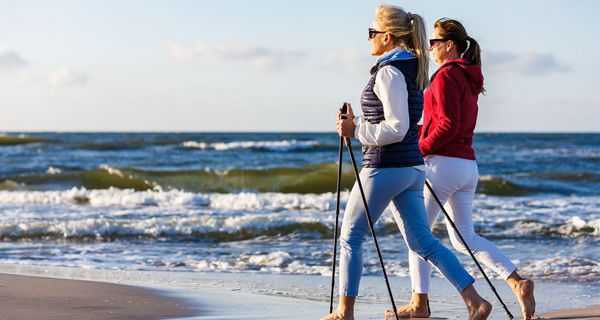 Zwei Frauen beim Nordic Walking am Strand.