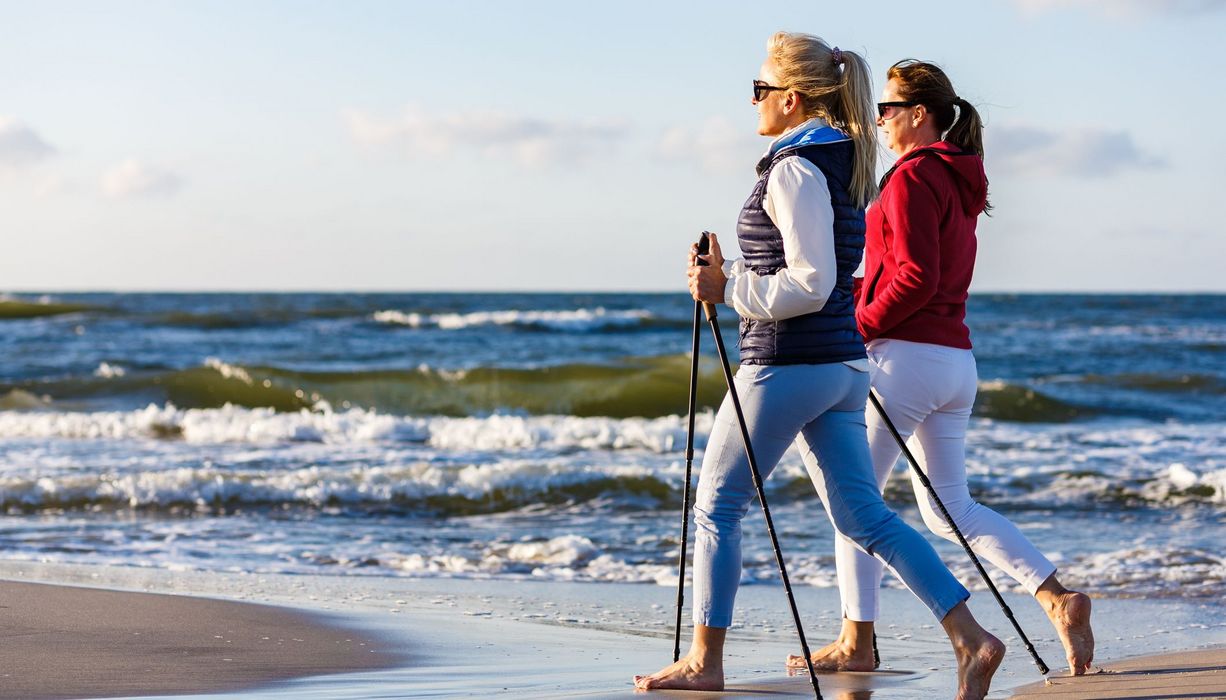 Zwei Frauen beim Nordic Walking am Strand.