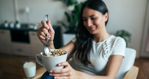 Junge Frau, isst ein Müsli.