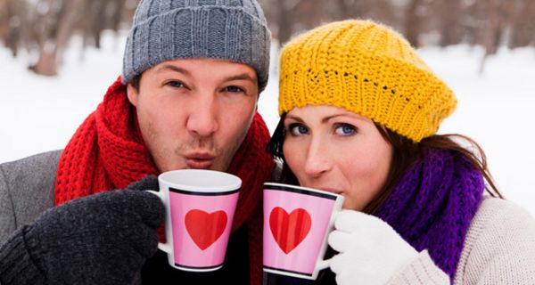 Junger Mann und junge Frau mit Teetassen im Schnee