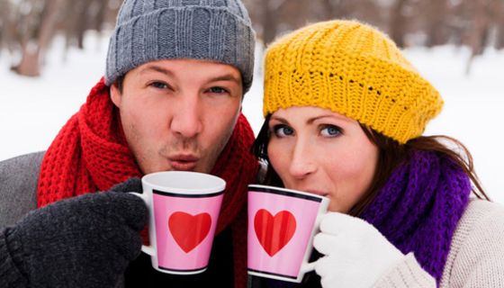 Junger Mann und junge Frau mit Teetassen im Schnee