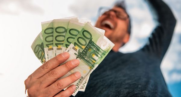 Mann hat ein Bündel Geldscheine in der Hand.