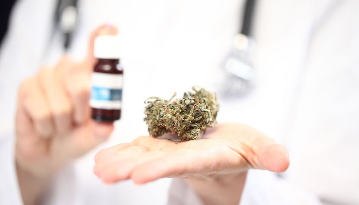 Arzt, hält medizinisches Cannabis in die Kamera.