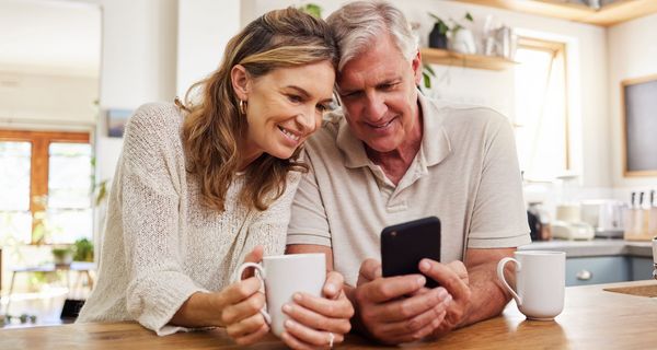Älteres Paar schaut gemeinsam auf ein Smartphone.