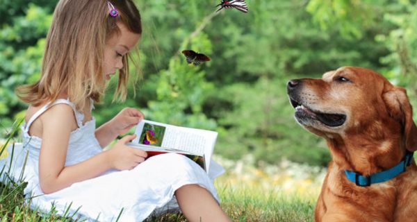 Mädchen liest einem Hund ein Buch vor